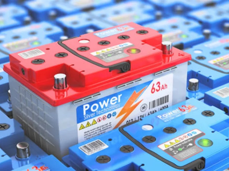 Red-topped automotive battery labeled Power 63Ah among blue batteries.